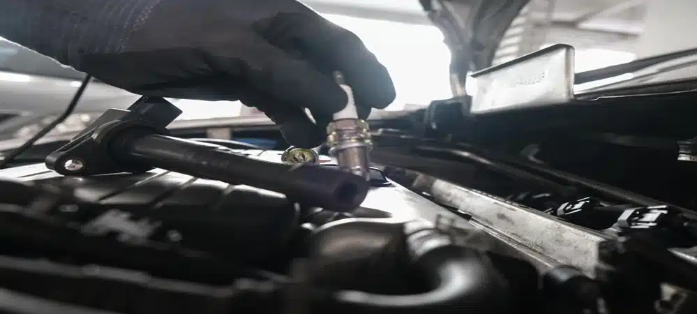 Auto technician replacing spark plugs on a vehicle engine with Northside Car Keys