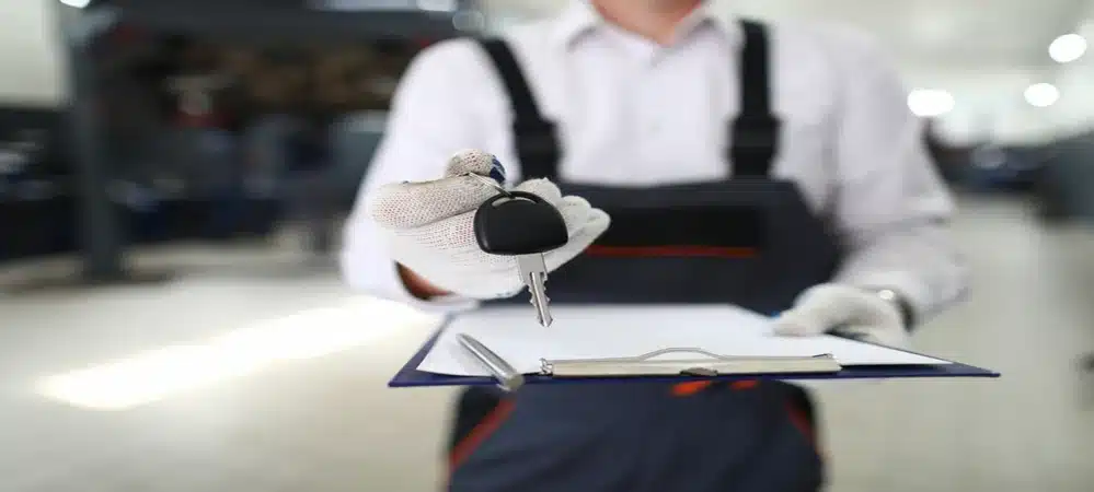 Auto locksmith holding a new car key and clipboard for Northside Car Keys services